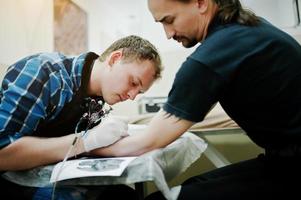 Tattoo-Meister machen Tattoo für Rocker-Mann im Tattoo-Salon foto