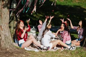 Fröhliche und sexy Mädchen sitzen am Picknicktisch und essen Erdbeeren auf Junggesellinnenabschied foto