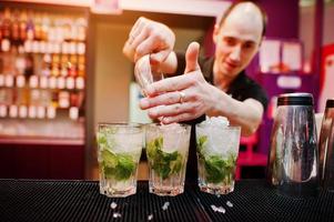 Barkeeper bereitet Mojito-Cocktailgetränk an der Bar zu foto