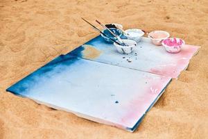 zwei bemalte Leinwände mit auf Sand liegenden Farbpaletten, Künstlerpalette beim Kunstfestival im Freien foto