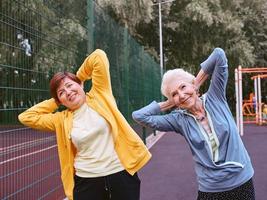 zwei reife frauen, die im park sportübungen machen. gesundes lebensstilkonzept foto