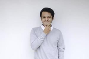 junger asiatischer mann trägt graues hemd mit denkender und schauender ideengeste foto
