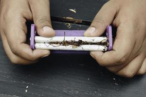 Die Hand des Mannes macht eine Zigarette mit rollenden traditionellen Werkzeugen, Hände in der Nähe. foto