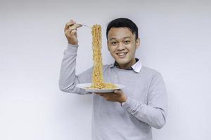 Porträt eines glücklichen jungen Asiaten genießt Nudeln. Konzept zum Mittagessen. foto