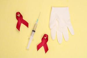 rotes band und symbol für medizinische geräte gegen hiv isoliert auf gelbem hintergrund foto