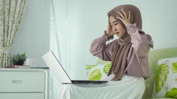 asiatische frau im hijab wird von ihrem laptop-bildschirm schwindelig foto