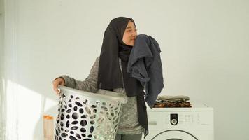 Schöne Frau im Hijab riecht den Duft von Kleidung zu Hause foto