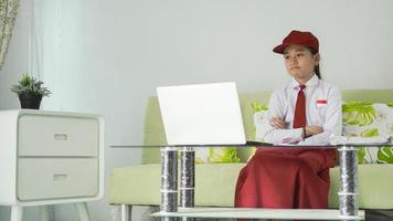 asiatisches grundschulmädchen, das von zu hause aus lernt und verärgert auf ihren laptop-bildschirm schaut foto