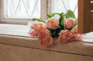 weich fokussierte rosa pfingstrosenblumen auf weißer fensterbank foto