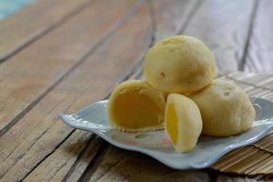 Mochi im thailändischen Stil mit Mungobohnenstapel auf weißem Teller und Holztisch mit Kopierplatz für Ihren Text. thailändischer süßer Nachtisch. foto