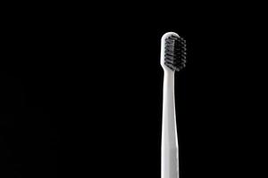 graue Zahnbürste mit schwarzen Borsten auf schwarzem Hintergrund isoliert. Platz für Text kopieren. Konzept des Gesundheitswesens. Zahnpflegekonzept. selektiver Fokus. foto