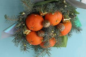 weihnachtsstrauß aus tannenzweigen, mandarinen und kleinen geschenkboxen auf blauem hintergrund. Neujahr. foto