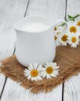 Krug mit Milch und Kamillenblüte foto