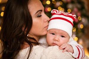 hübsche junge Frau mit einjährigem Baby im Arm, vor Hintergrund foto