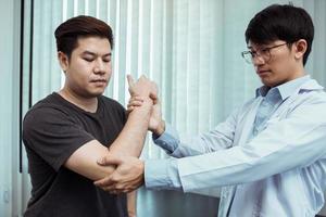 asiatische Physiotherapeuten kontrollieren die Ellenbogen von Patienten nach orthopädischer Rehabilitation. foto