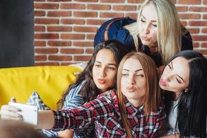 vier schöne junge frau, die selfie in einem café machen, beste freundinnen, die zusammen spaß haben, emotionales lebensstil-menschenkonzept aufwerfen foto