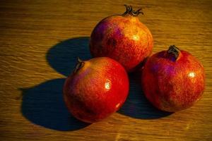drei reife Granatäpfel auf dem Holztisch foto