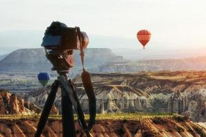 heißluftballon, der über felslandschaft in der türkei fliegt. DSLR-Kamera auf einem Stativ im Vordergrund foto