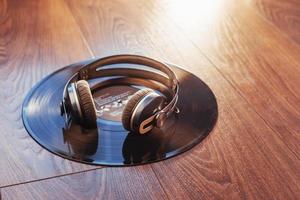 Schallplatte und Kopfhörer über Holztisch. Audio-Enthusiasten, Musikliebhaber oder professionelle Discjockey-Ausrüstung. foto