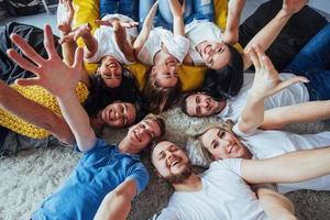 gruppieren sie schöne junge leute, die selfie machen, die auf dem boden liegen, beste freunde mädchen und jungen, die zusammen spaß haben und emotionales lebensstilkonzept posieren foto