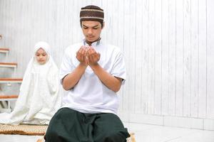 junger muslimischer mann und frau beten zusammen zu hause. foto