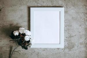 weiße Leerstelle in der Mitte des weißen Rahmens mit Rosenblüte, verspottet foto