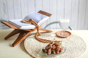 kurma oder dattelfrucht mit glas wasser, heiligem koran und gebetsperlen auf dem tisch. traditionelles ramadan, iftar-mahlzeit. ramadan kareem fastenmonatskonzept foto