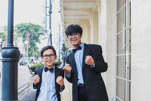 Zwei Teenager im schwarzen Vintage-Anzug posieren und lächeln in die Kamera, während sie Erfolg oder Ja-Gesten zeigen foto