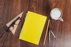 auf hölzernem Hintergrund Notebook-Bleistift, Kaffee und Blumen. foto