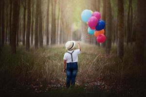 Kind mit Luftballons im Wald foto