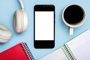 smartphone mit weißem bildschirm für kopierraum mit notizbüchern, kopfhörer und tasse kaffee foto