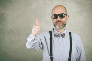 glücklicher mann mit sonnenbrille und fliege, die daumen hoch zeigt foto