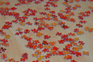 Viele rote Puzzlesteine sind auf dem Holzboden verstreut foto