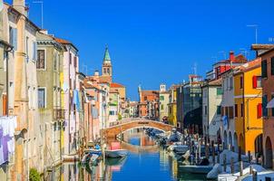 chioggia-stadtbild mit schmalem wasserkanal vena mit festgemachten bunten booten zwischen alten bunten gebäuden foto