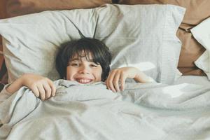glückliches Kind, das auf dem Bett liegt foto