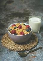 Schüssel Cornflakes, Heidelbeeren, Himbeeren und ein Glas Milch foto