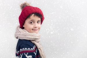 lächelnder Junge mit Schal und Mütze im Winter foto