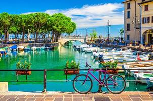 Fahrrad in der Nähe des Zauns des alten Hafens von Porto Vecchio mit Motorbooten auf türkisfarbenem Wasser foto