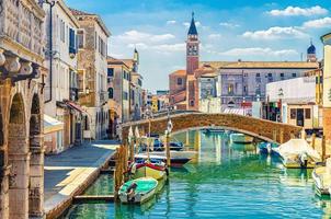 chioggia-stadtbild mit schmalem wasserkanal mit festgemachten bunten booten, alten gebäuden foto