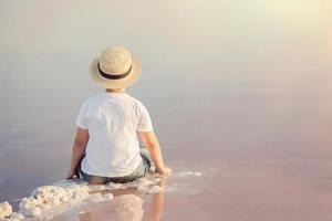 Trauriger und nachdenklicher Junge, der am Strand sitzt foto