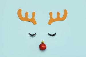 frohe weihnachten.weihnachten rudolph-renhörner mit falschen wimpern und rotem weihnachtsball.weihnachtskonzepthintergrund foto