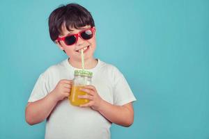 glücklicher Junge, der Orangensaft trinkt foto