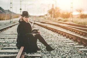 junge frau, die zug auf dem bahnsteig des bahnhofs wartet foto