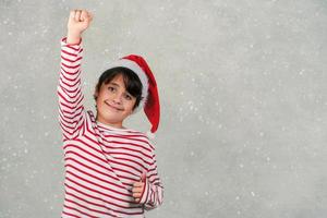 Frohe Weihnachten. Lächelndes Kind mit Weihnachtsmann-Hut foto