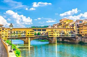 ponte vecchio steinbrücke mit bunten gebäudehäusern über den fluss arno foto