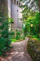 Kopfsteinpflasterweg mit Straßenlaterne in der Nähe der Wand aus mittelalterlichem Burgturm aus Steinziegeln