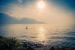Mann auf einem Surfbrett mit Paddel auf dem Genfer See, Schweiz foto