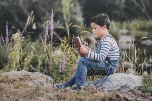 Kind sitzt und liest ein Buch auf dem Feld foto