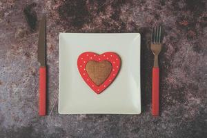 rotes Herz auf einem weißen Teller neben Besteck foto