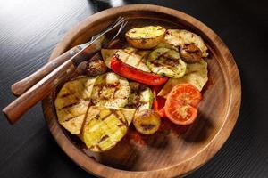 Reihe von gebackenem Gemüse Zucchini Tomaten Kartoffeln Paprika auf Holzplatte foto